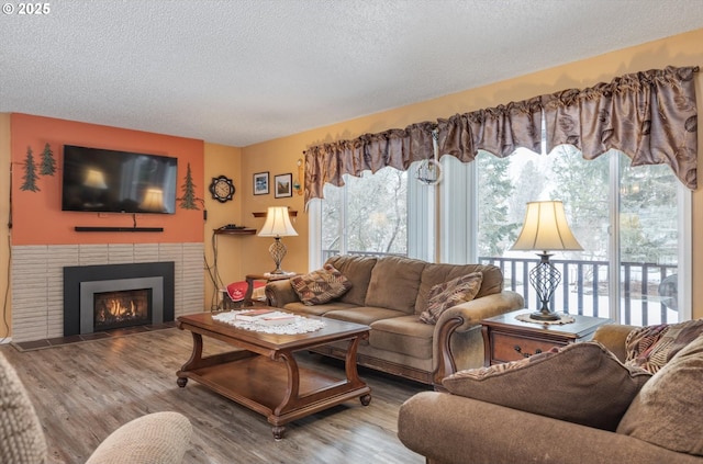 living area featuring a healthy amount of sunlight, a fireplace, a textured ceiling, and wood finished floors