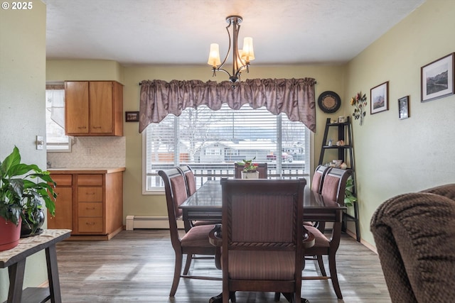 dining room featuring a notable chandelier, light wood-style floors, a wealth of natural light, and a baseboard radiator