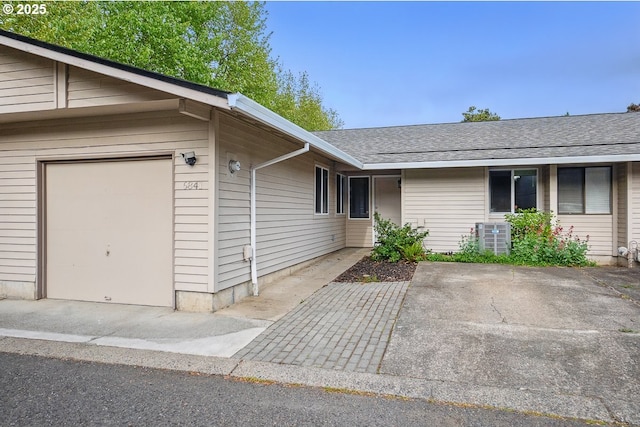 6841 SW Sussex St, Beaverton, OR 97008 - doorway to property with an attached garage, a shingled roof, and cooling unit