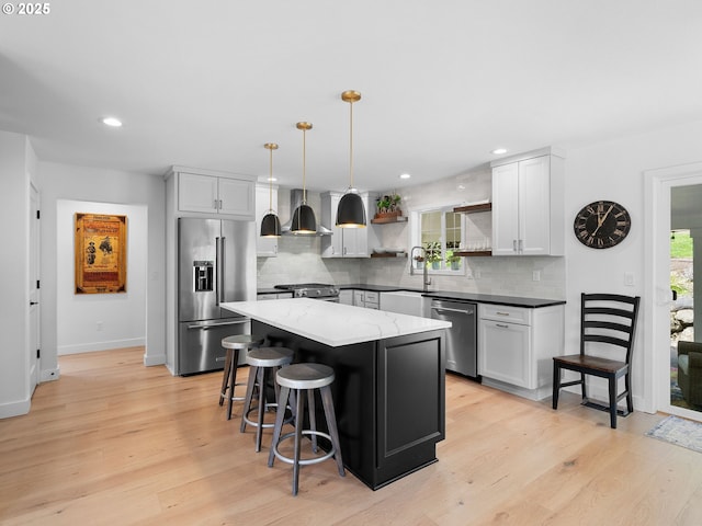 kitchen featuring open shelves, wall chimney range hood, light wood finished floors, appliances with stainless steel finishes, and backsplash