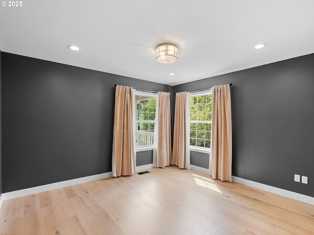 spare room with baseboards, recessed lighting, light wood finished floors, and visible vents