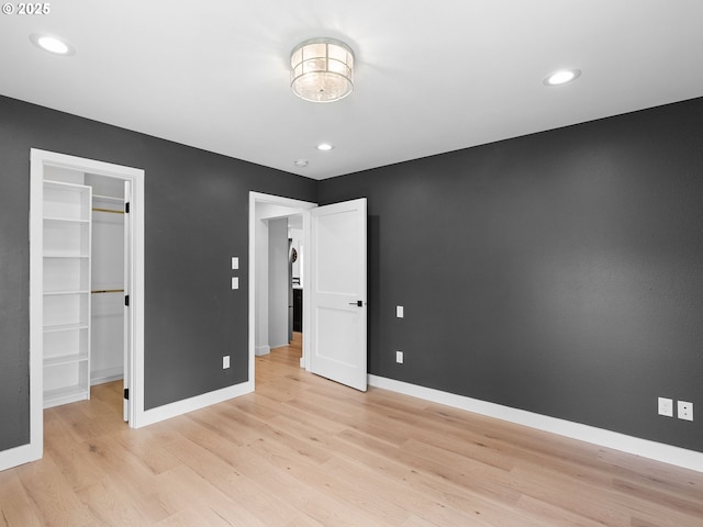 unfurnished bedroom with light wood-style floors, baseboards, recessed lighting, and a spacious closet