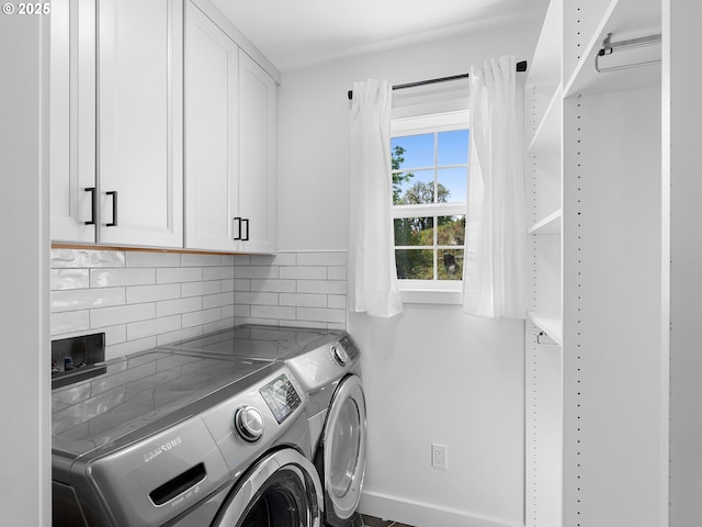 washroom with baseboards, cabinet space, and washer and clothes dryer