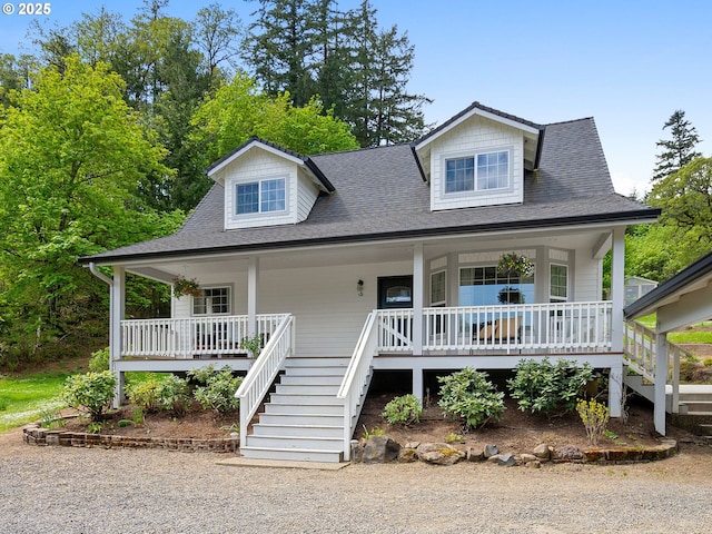 view of front facade featuring a shingled roof, a porch, and stairway
