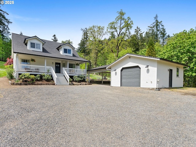 cape cod-style house with a garage, covered porch, gravel driveway, an outbuilding, and stairway