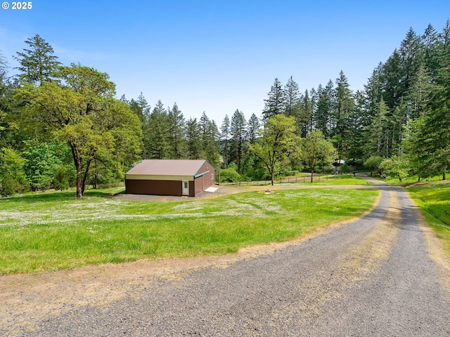 view of road featuring a wooded view and an outbuilding