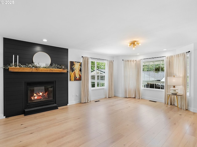 unfurnished living room with visible vents, a fireplace, wood finished floors, baseboards, and recessed lighting