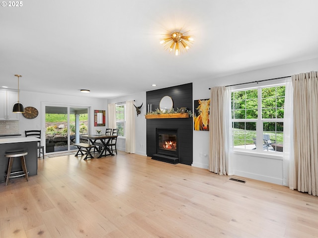 living room featuring baseboards, a fireplace, light wood-style flooring, and visible vents