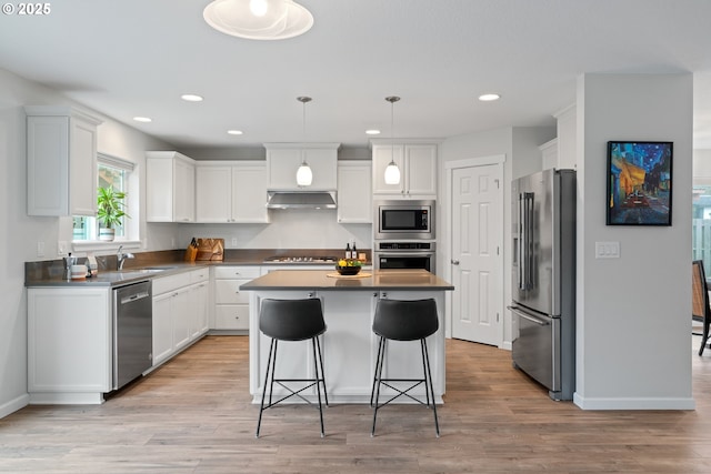 kitchen with white cabinets, stainless steel appliances, a center island, and hanging light fixtures