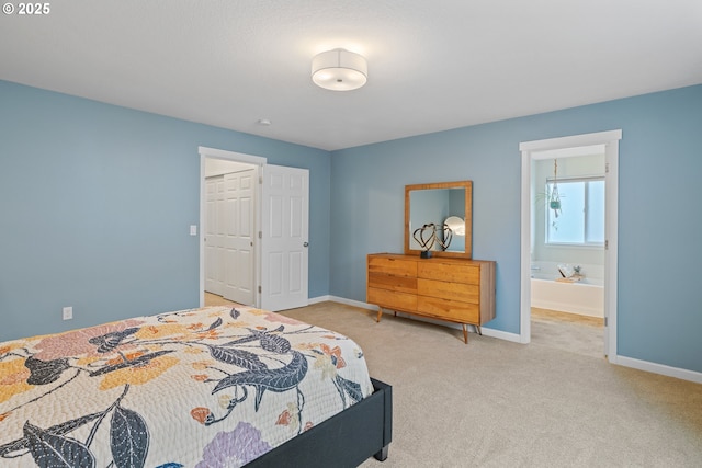 bedroom featuring light colored carpet, a closet, ensuite bath, and a walk in closet