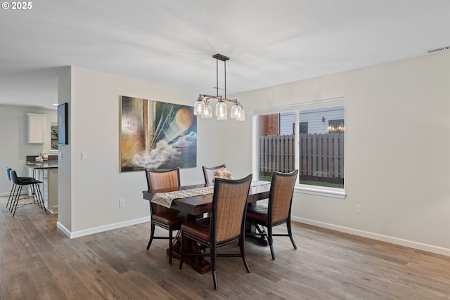 dining space with wood-type flooring and a notable chandelier