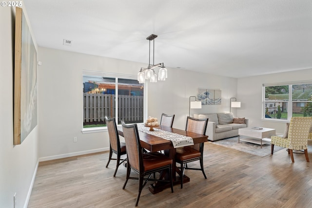 dining space with an inviting chandelier, light hardwood / wood-style flooring, and a wealth of natural light