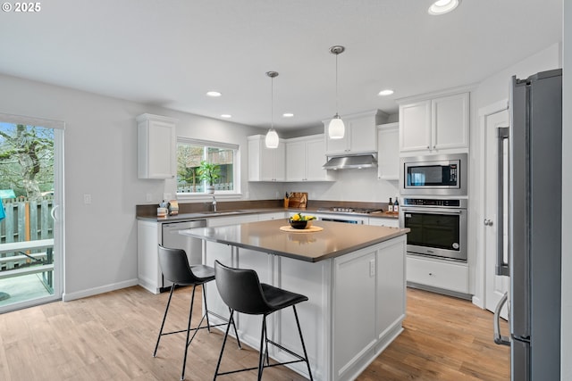 kitchen with a center island, appliances with stainless steel finishes, hanging light fixtures, and white cabinetry