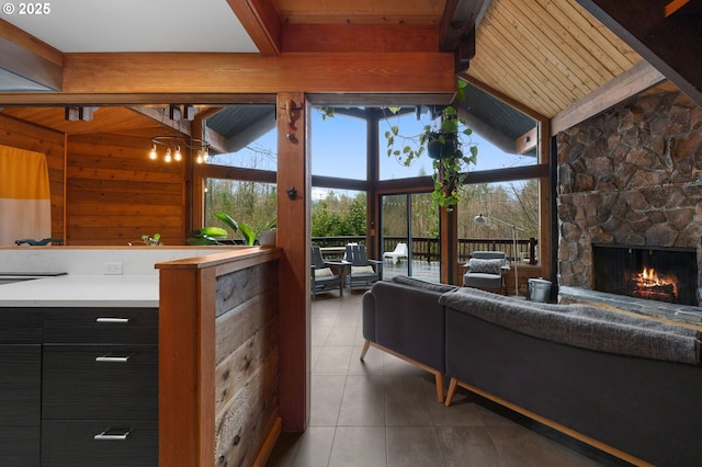 living area with wooden walls, a fireplace, vaulted ceiling with beams, and tile patterned flooring