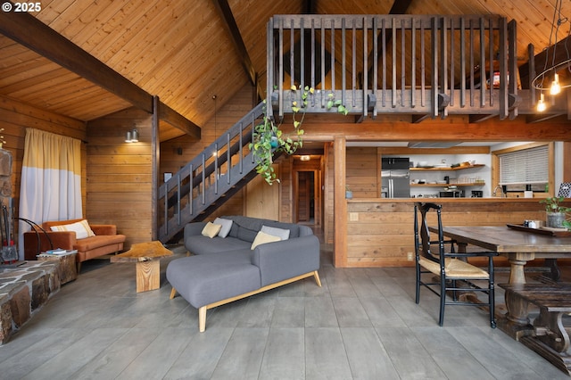 living area featuring stairway, wooden walls, beamed ceiling, and wooden ceiling