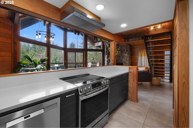 kitchen with stainless steel appliances, wooden walls, wooden ceiling, light countertops, and light tile patterned floors