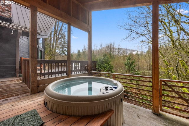 wooden terrace featuring a forest view and hot tub deck surround