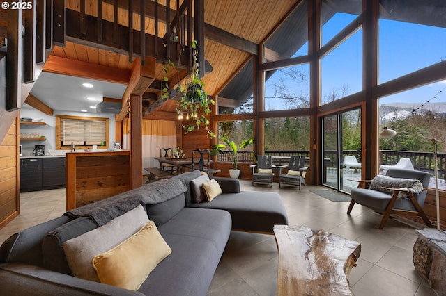 tiled living room featuring beamed ceiling, wooden ceiling, a wall of windows, and wooden walls