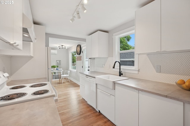 kitchen with a sink, white appliances, light wood-style flooring, and plenty of natural light