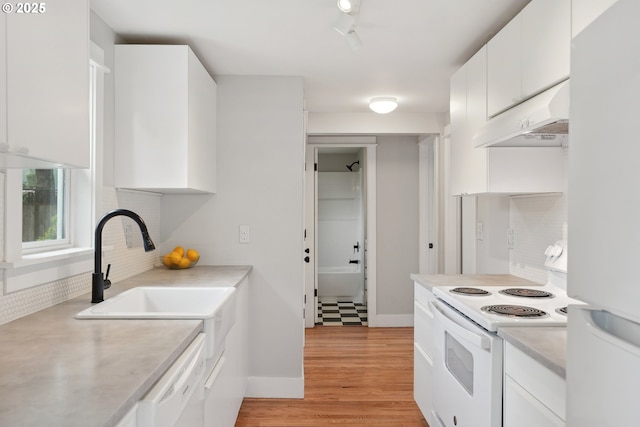 kitchen with white appliances, under cabinet range hood, decorative backsplash, white cabinets, and light countertops