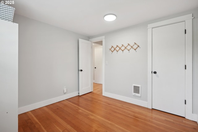 unfurnished bedroom with light wood-style flooring, baseboards, and a closet