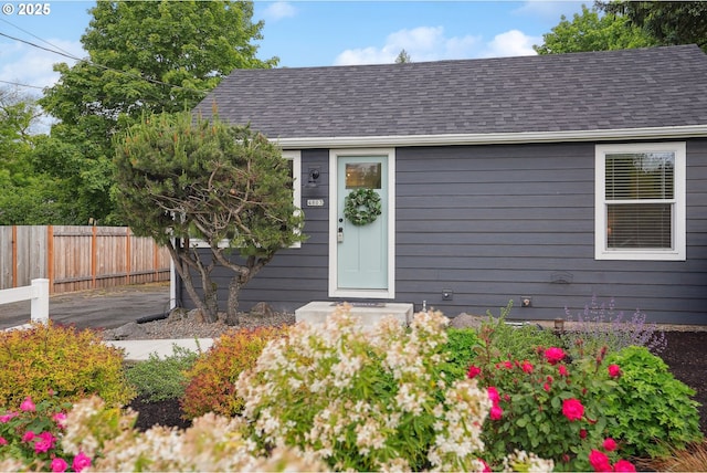 view of front facade featuring fence and a shingled roof