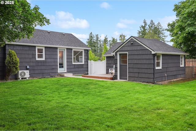 back of house with a cooling unit, a shingled roof, and an outdoor structure