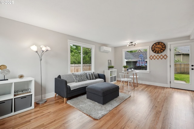 living area with a wall unit AC, light wood finished floors, and baseboards