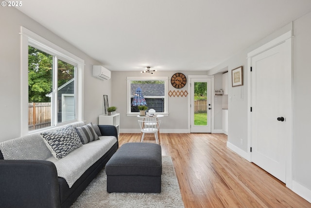 living area featuring a wall mounted AC, light wood-style flooring, healthy amount of natural light, and baseboards