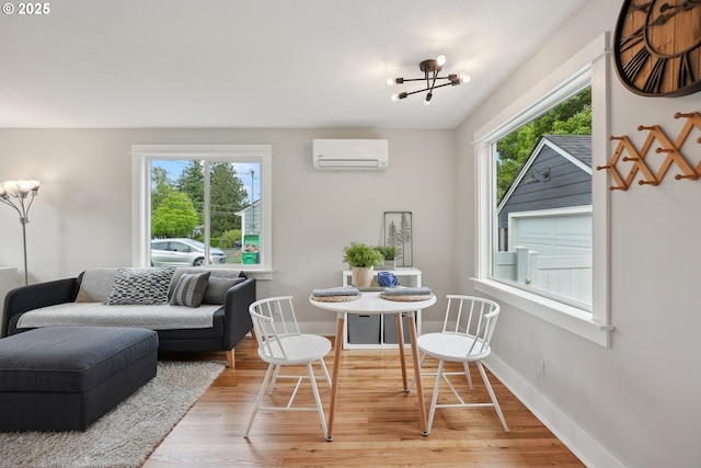 dining room featuring a wall mounted AC, plenty of natural light, a chandelier, and light wood finished floors
