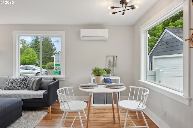 dining room featuring an AC wall unit, wood finished floors, baseboards, and a chandelier