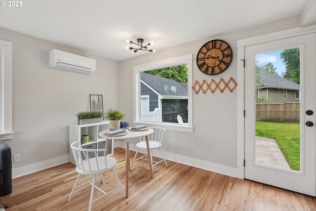dining room featuring an AC wall unit, wood finished floors, baseboards, and a chandelier