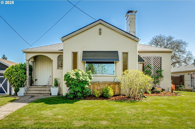 view of front of home featuring a shingled roof, a chimney, stucco siding, and a front lawn