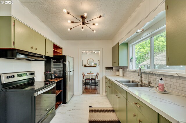 kitchen with green cabinetry, under cabinet range hood, a chandelier, a sink, and appliances with stainless steel finishes