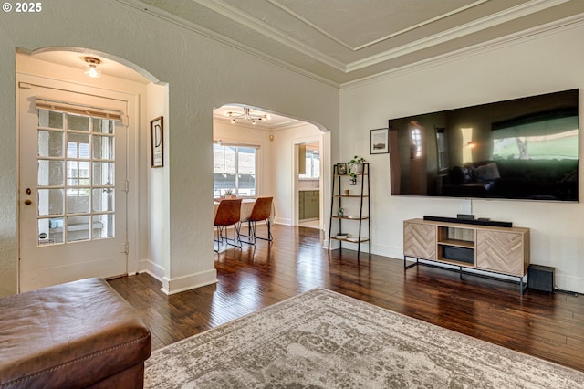 living area with an inviting chandelier, ornamental molding, a textured wall, hardwood / wood-style flooring, and arched walkways