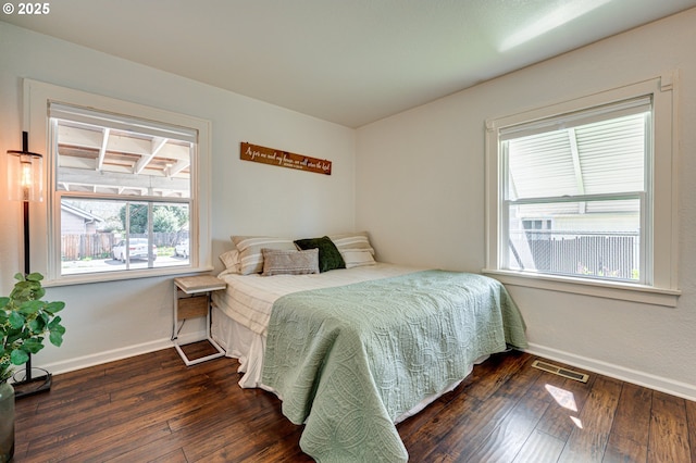 bedroom featuring visible vents, baseboards, multiple windows, and hardwood / wood-style flooring
