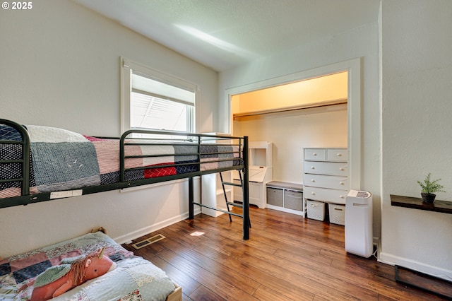 bedroom with baseboards, visible vents, and hardwood / wood-style floors