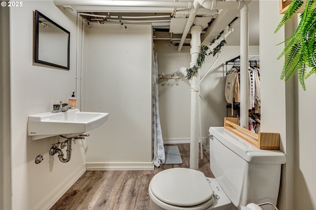 bathroom featuring a sink, baseboards, toilet, and wood finished floors