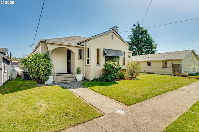 bungalow-style home with a front lawn, fence, stucco siding, a chimney, and central air condition unit