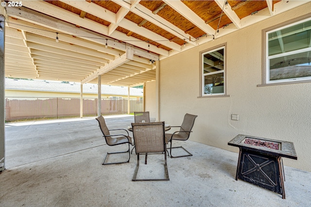 view of patio with fence, outdoor dining space, and a fire pit