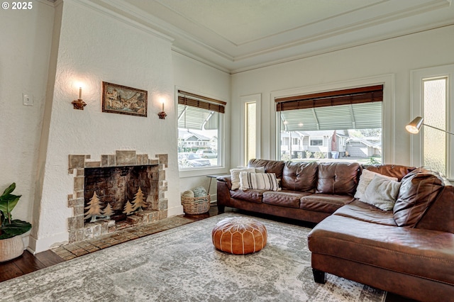 living area with crown molding, a textured wall, a fireplace, baseboards, and wood finished floors
