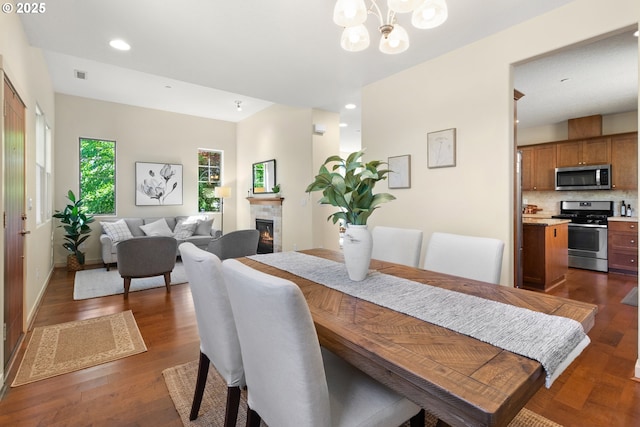 29229 SW Costa Cir E, Wilsonville, OR 97070 - dining space featuring a chandelier, a glass covered fireplace, recessed lighting, dark wood finished floors, and baseboards