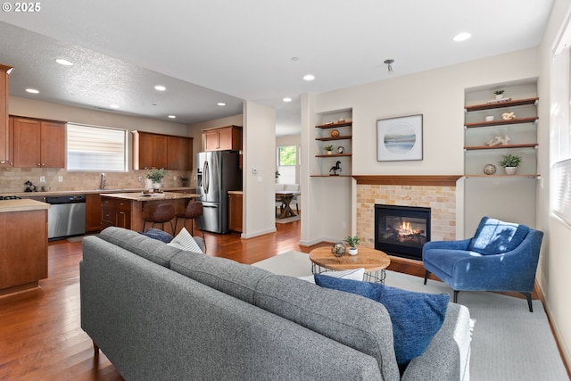 29229 SW Costa Cir E, Wilsonville, OR 97070 - living room featuring wood finished floors, a brick fireplace, baseboards, recessed lighting, and built in shelves