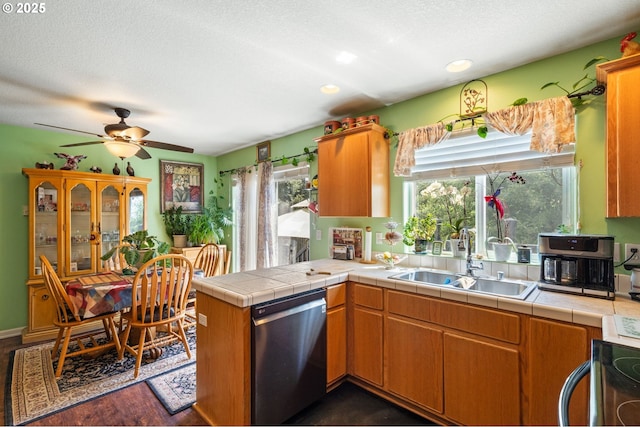 kitchen featuring stainless steel dishwasher, a sink, plenty of natural light, a peninsula, and a textured ceiling