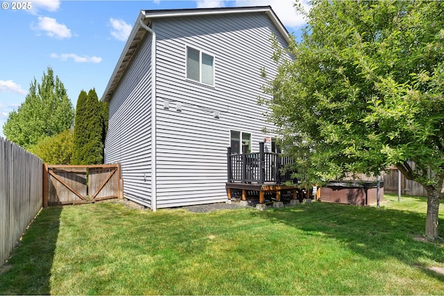 rear view of house with a wooden deck and a hot tub