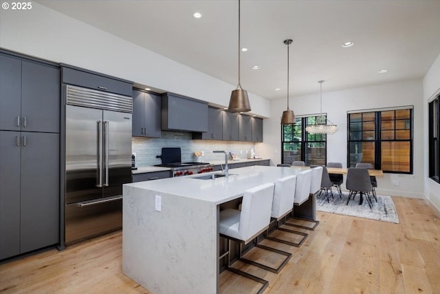 542 4th St, Lake Oswego, OR 97034 - kitchen with stainless steel built in fridge, light wood-style flooring, decorative backsplash, light countertops, and pendant lighting