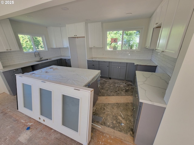 kitchen with gray cabinetry, backsplash, plenty of natural light, and sink