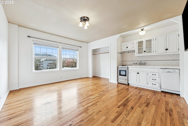 kitchen with electric range, white cabinetry, light wood-style floors, dishwasher, and tasteful backsplash