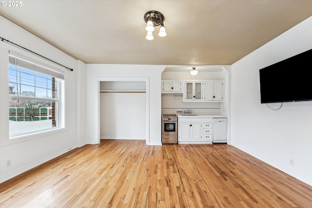 unfurnished living room with a sink, light wood-style flooring, and baseboards