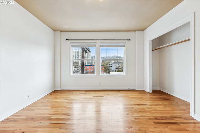 unfurnished bedroom with light wood finished floors, baseboards, and a closet